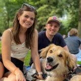 Zwei junge Frauen und ein Mann sitzen auf einer blauen Picknick-Decke im Dortmunder Westpark. Eine der Frauen trinkt ein alkoholfreies Radler. Ebenfalls auf der Decke sitzt ein Hund.