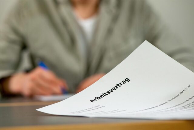 Ein Mann unterschreibt einen Arbeitsvertrag.