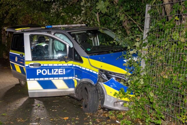 Ein beschädigtes Polizeifahrzeug steht nach einer Verfolgungsjagd an einem Zaun.