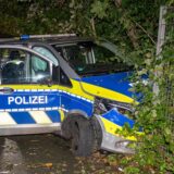 Ein beschädigtes Polizeifahrzeug steht nach einer Verfolgungsjagd an einem Zaun.