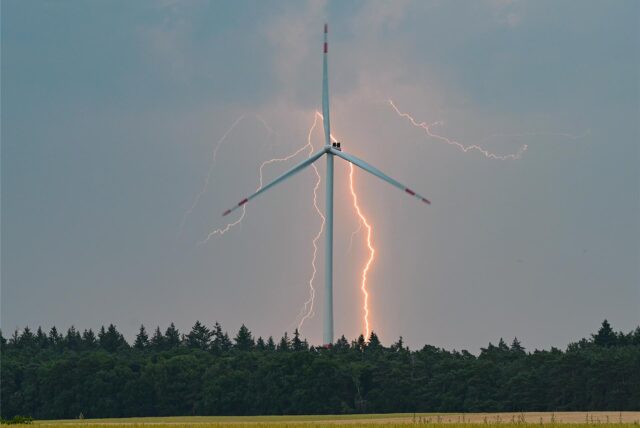 Blitze sind während eines Gewitters hinter einer Windkraftanlage zu sehen