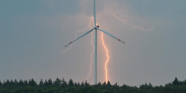 Blitze sind während eines Gewitters hinter einer Windkraftanlage zu sehen