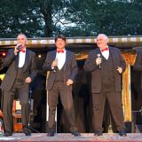 Vier Mitglieder der Band „Bühnenreif“ stehen im Elsebad in Schwerte-Ergste auf der Bühne. Sie tragen Anzüge mit roten Fliegen und singen in Mikrofone.