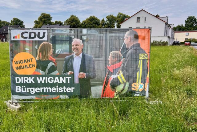 Ein Wahlplakat der CDU steht auf einem Feld.