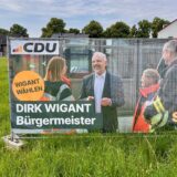 Ein Wahlplakat der CDU steht auf einem Feld.
