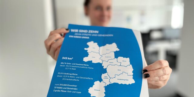 Eine Frau hält eine Karte des Kreises Unna.