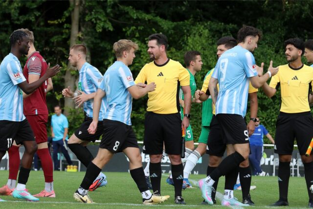 Spieler und Schiedsrichter klatschen sich ab.