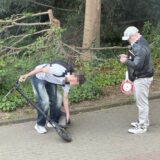 Ein Jugendlicher hantiert an einem E-Scooter, während ein Zivilpolizist daneben steht und etwas notiert. Der Vorfall ereignete sich auf einem Gehweg am Ostring in Unna, im Hintergrund ist Bewuchs zu erkennen.