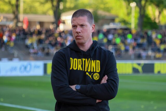 Mike Tullberg steht mit verschränkten Armen vor der Brust im Stadion Rote Erde.