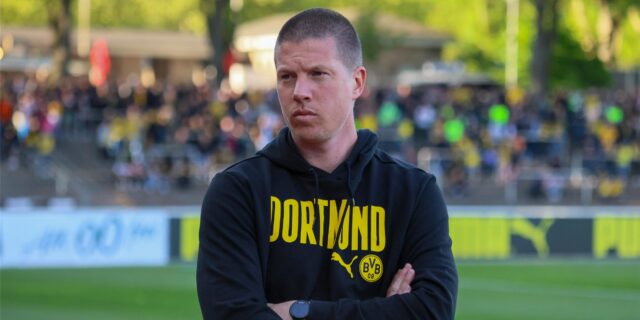 Mike Tullberg steht mit verschränkten Armen vor der Brust im Stadion Rote Erde.