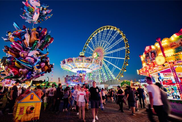 Blick auf die beleuchteten Fahrgeschäfte der Cranger Kirmes, darunter ein Riesenrad.