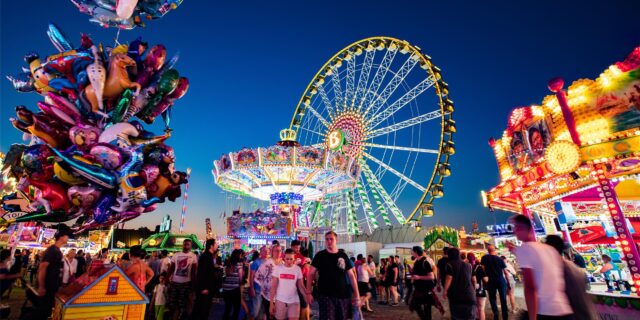 Blick auf die beleuchteten Fahrgeschäfte der Cranger Kirmes, darunter ein Riesenrad.