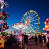 Blick auf die beleuchteten Fahrgeschäfte der Cranger Kirmes, darunter ein Riesenrad.