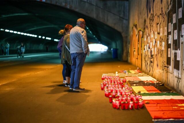 Betroffene stehen im Tunnel in der Nähe des Unglücksortes vor Kerzen, die das Datum 24.07.2010 zeigen.