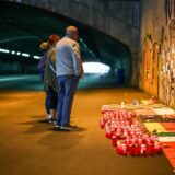 Betroffene stehen im Tunnel in der Nähe des Unglücksortes vor Kerzen, die das Datum 24.07.2010 zeigen.