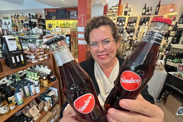 Katja Vogt hält in ihrem Restaurant und Feinkostladen Refugio zwei Flaschen Sinalco-Cola in die Kamera.