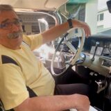 Mauricio Correia aus Schwerte sitzt in seinem Cadillac „Sand DeVille“ und lächelt in die Kamera.