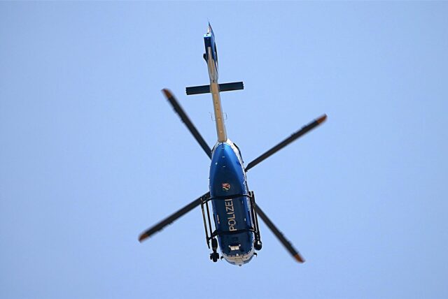 Ein Hubschrauber der Polizei hebt sich im Überflug gegen den wolkenlosen Himmel ab.
