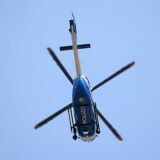 Ein Hubschrauber der Polizei hebt sich im Überflug gegen den wolkenlosen Himmel ab.